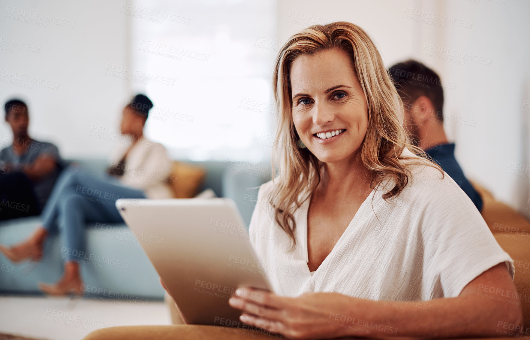 Buy stock photo Cropped portrait of an attractive young businesswoman sitting and using a tablet while her colleagues work behind her