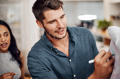 Buy stock photo Cropped shot of a handsome young businessman using a visual aid to brainstorm with his colleagues in the office