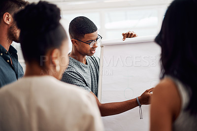 Buy stock photo Cropped shot of a diverse group of businesspeople standing together and using a visual aid to brainstorm in the office