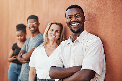 Buy stock photo Cropped portrait of a handsome young businessman standing with his colleagues against a wall outside