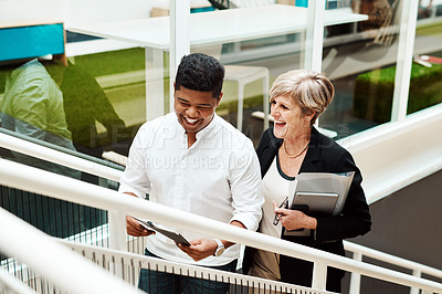 Buy stock photo Shot of two businesspeople walking up a staircase together in an office