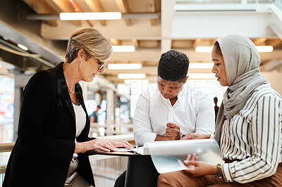 Buy stock photo Shot of a group of businesspeople going through paperwork together in an office