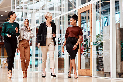 Buy stock photo Shot of a group of businesswomen walking alongside each other in an office