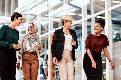 Buy stock photo Shot of a group of businesswomen walking alongside each other in an office