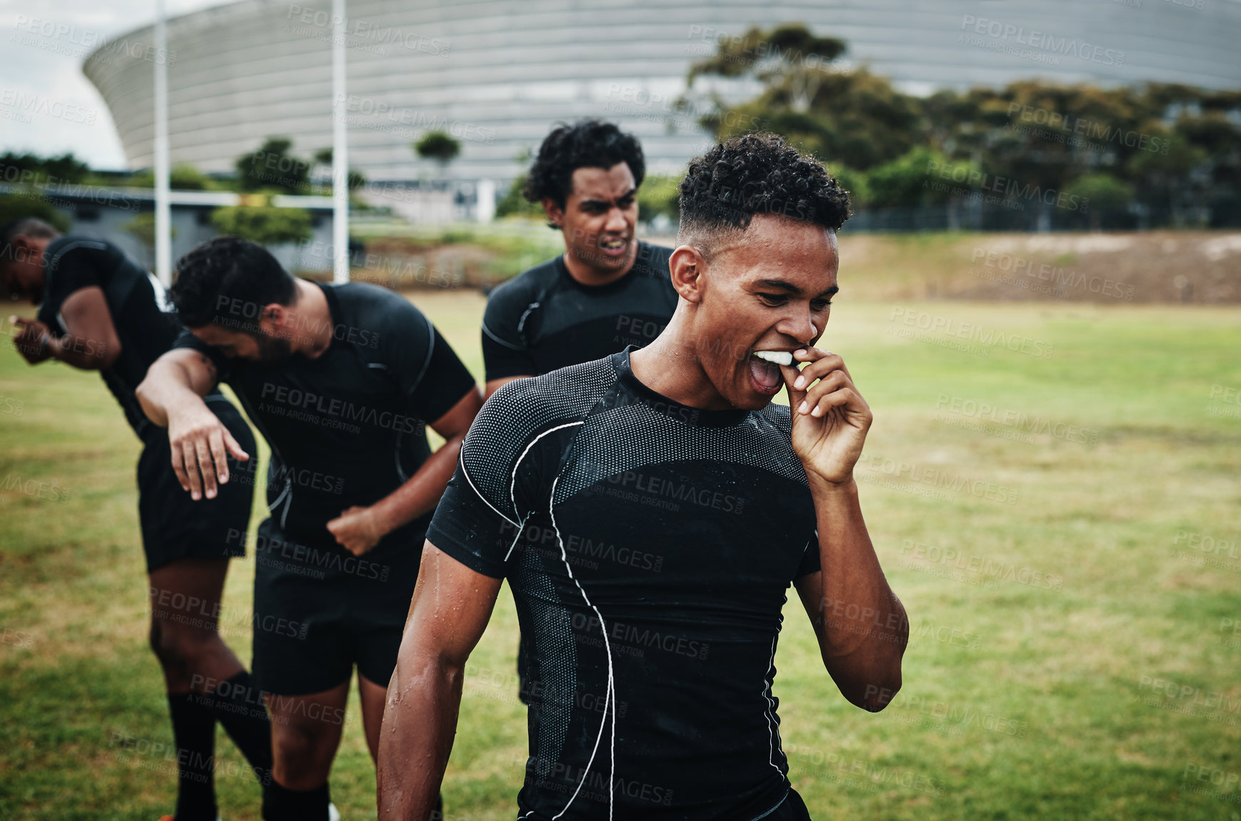 Buy stock photo Cropped shot of a handsome young rugby player removing his mouthguard during half-time on the field