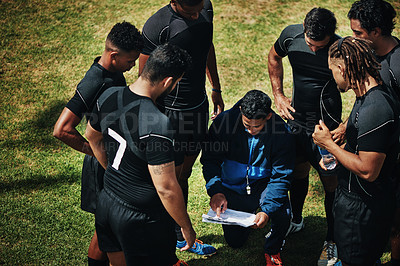 Buy stock photo High angle shot of a handsome young rugby coach addressing his team on the field during the day