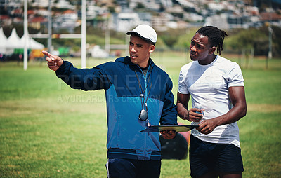 Buy stock photo Cropped shot of a handsome young rugby coach talking to one of his players on the field during the day