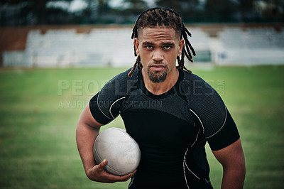 Buy stock photo Cropped portrait of a handsome young rugby player holding a rugby ball while standing on the field
