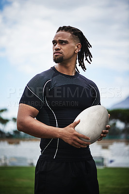 Buy stock photo Cropped shot of a handsome young rugby player holding a rugby ball while standing on the field