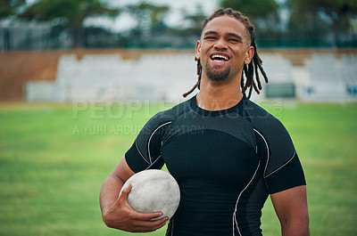 Buy stock photo Cropped portrait of a handsome young rugby player smiling while holding a rugby ball on the field