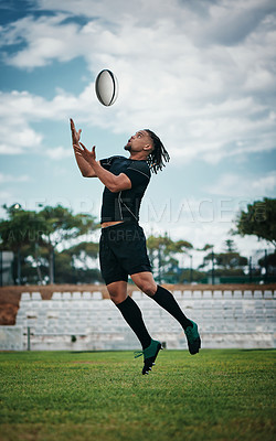 Buy stock photo Full length shot of a handsome young rugby player catching a ball mid-air on the field