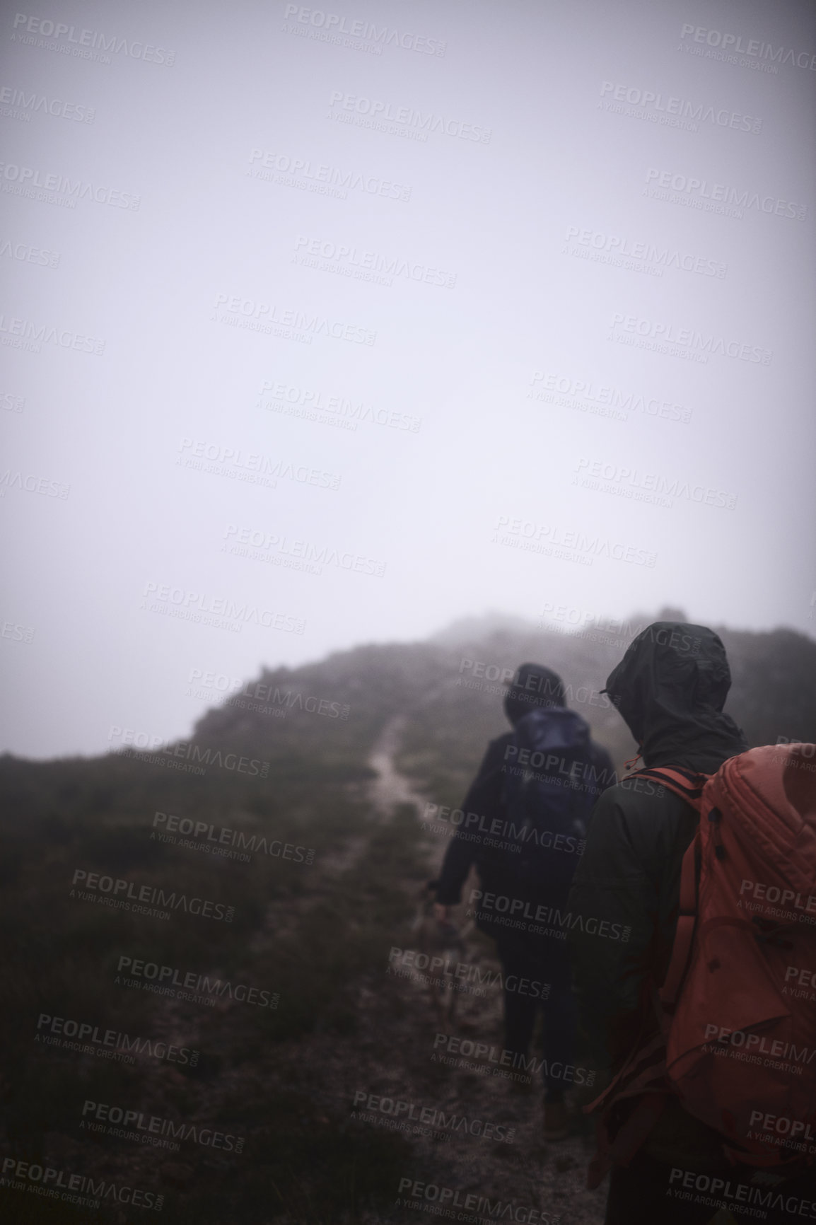 Buy stock photo Shot of two male friends out hiking in the mountains on a foggy day