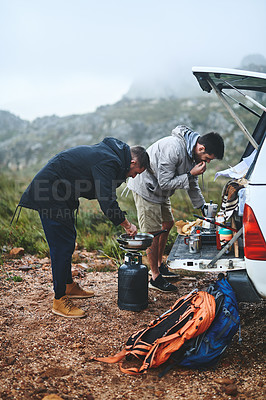 Buy stock photo Shot of two male friends preparing breakfast while out in the mountains