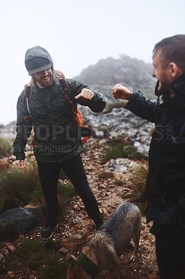 Buy stock photo Shot of two male friends fist bumping while out for a hike in the mountains