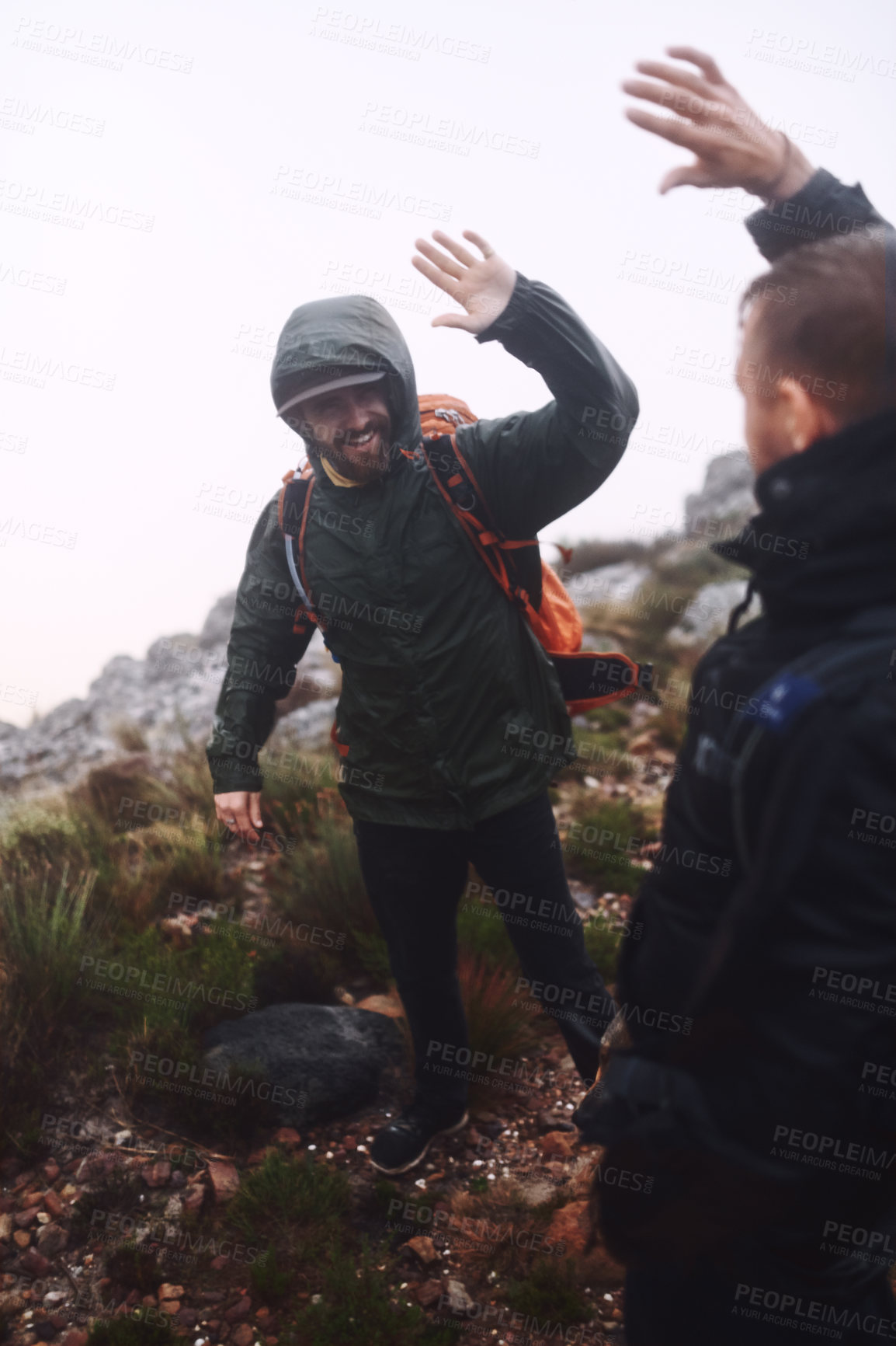 Buy stock photo Shot of two male friends giving each other a high-five while out hiking in the mountains