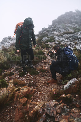 Buy stock photo Shot of two male friends out for a hike in the mountains with a dog