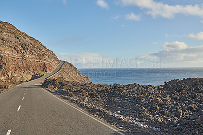 Buy stock photo Tar road or street leading to scenic mountains with sea view during summer roadtrip in La Palma, Canary Islands, Spain. Landscape of a rocky ocean mountain pass with blue sky, clouds and copy space 