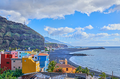 Buy stock photo A colorful and vibrant city Port of Tazacorte, La Palme, Spain. Beautiful landscape of an urban town near the beach and mountains with a cloudy blue sky. Bright buildings near the sea or ocean
