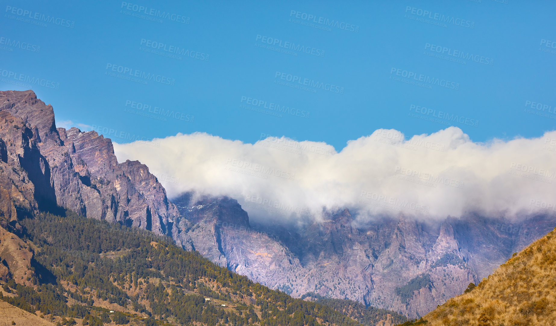 Buy stock photo Beautiful landscape of a mountain top covered in clouds with clear blue sky copy space above and hills below. A peaceful and scenic panoramic view of a peak or summit on a bright and sunny summer day