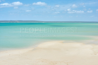 Buy stock photo Copyspace at the sea with a blue sky and mountain background above the horizon. Calm blue ocean water at an empty beach shore. Peaceful scenic coastal landscape for a relaxing and zen summer getaway
