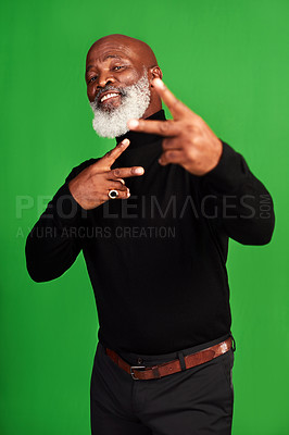 Buy stock photo Studio shot of a senior man showing peace signs while posing against a green background