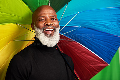 Buy stock photo Shot of a senior man posing with a colorful umbrella over his head