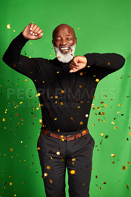 Buy stock photo Shot of a senior man dancing while confetti falls over him against a green background