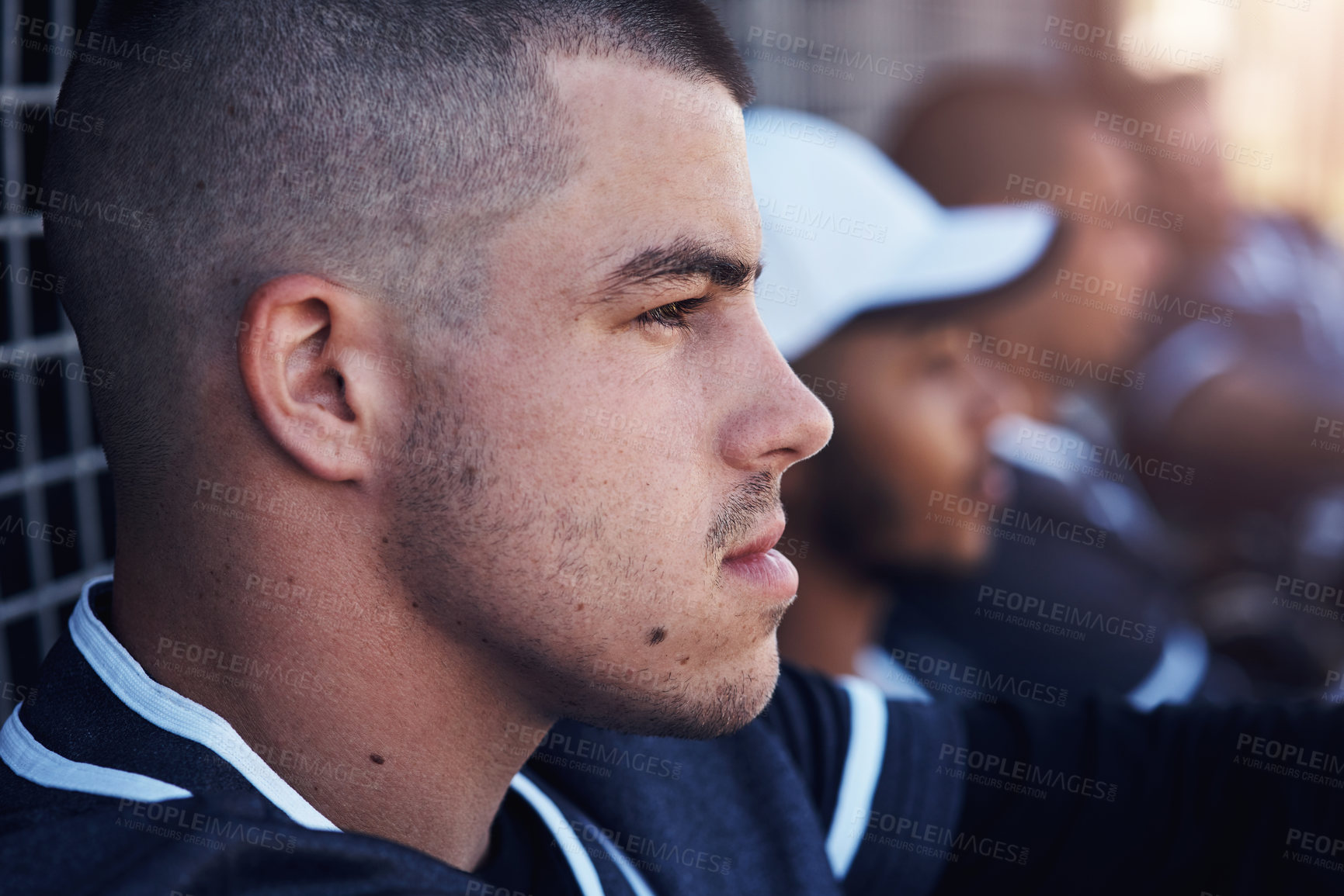 Buy stock photo Shot of a young man watching a baseball game with his team mates