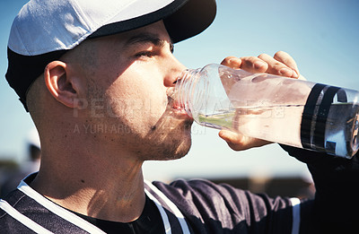 Buy stock photo Shot of a young man drinking water after playing a game of baseball