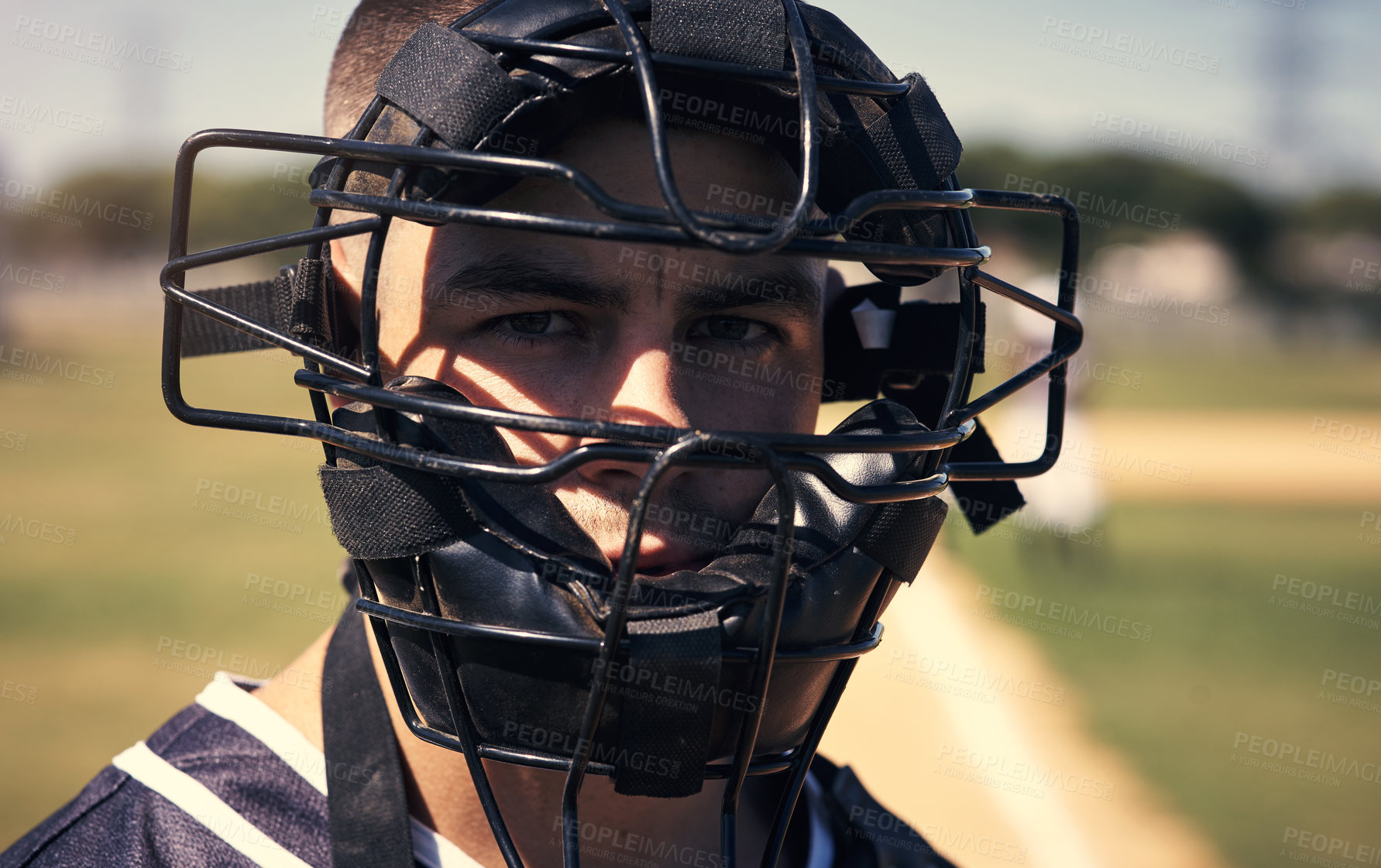 Buy stock photo Portrait of a young man wearing a catchers helmet while playing a game of baseball