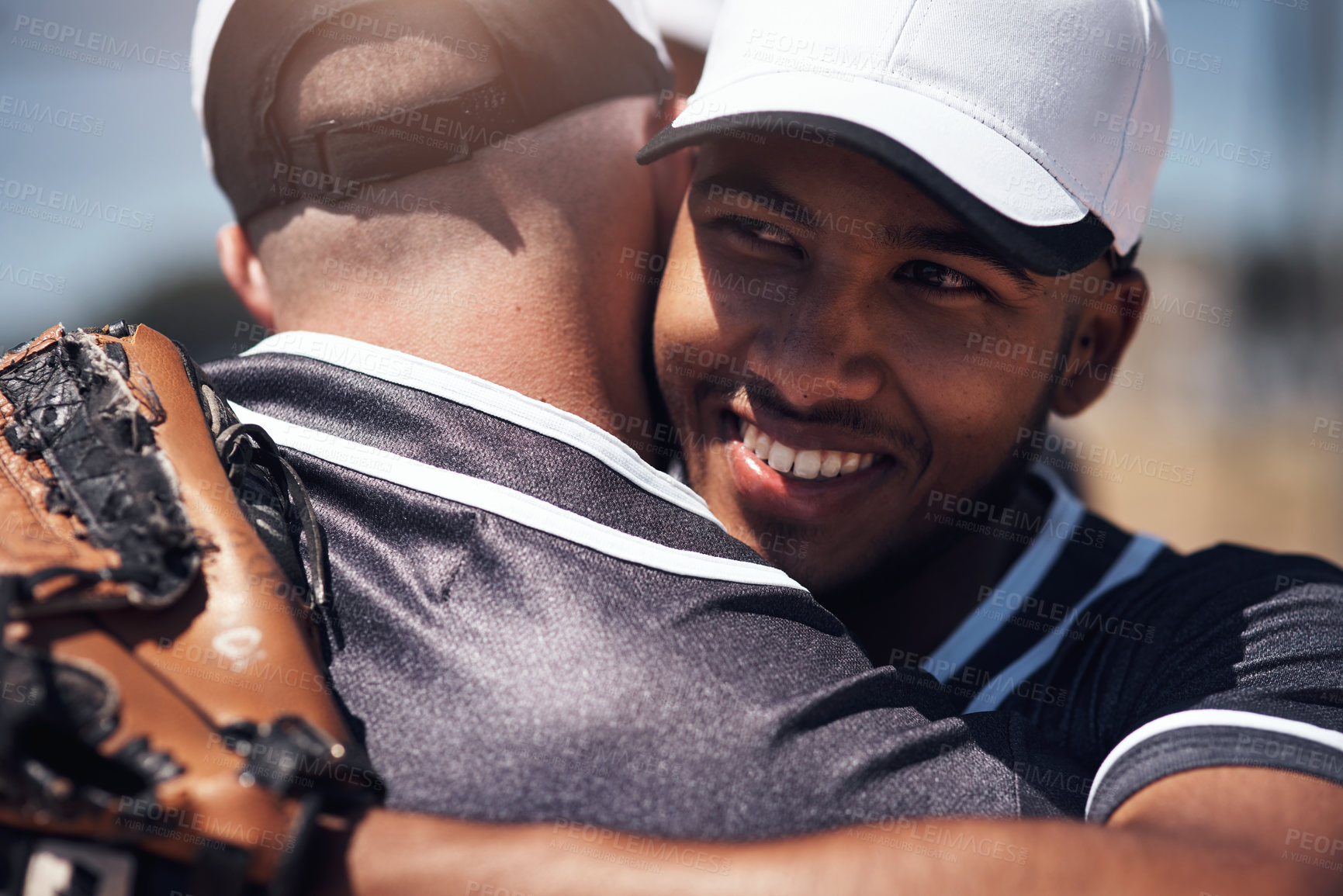 Buy stock photo Shot of two young men embracing after playing a game of baseball