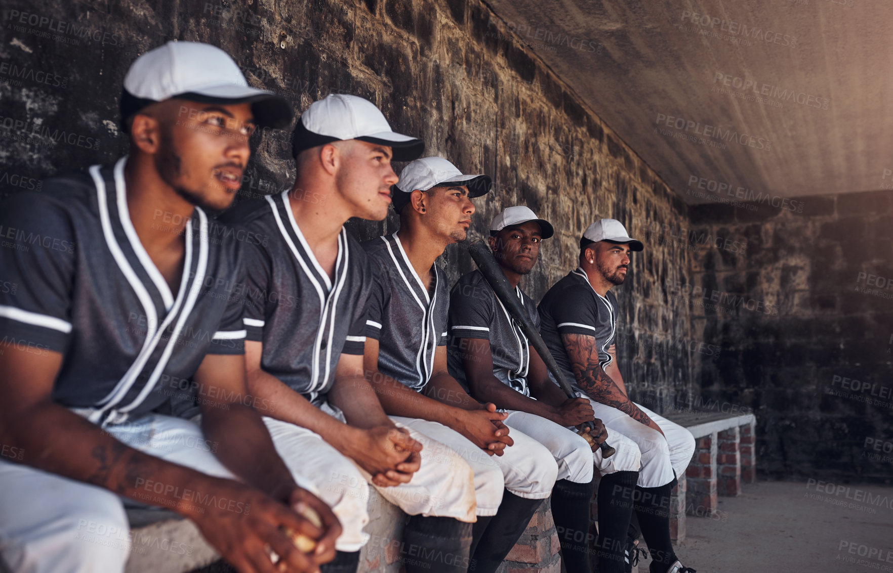 Buy stock photo Shot of a group of young men watching a game of baseball from the dugout