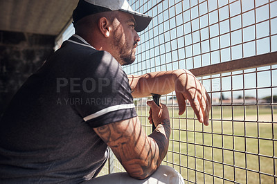 Buy stock photo Shot of a young man watching a game of baseball from behind the fence
