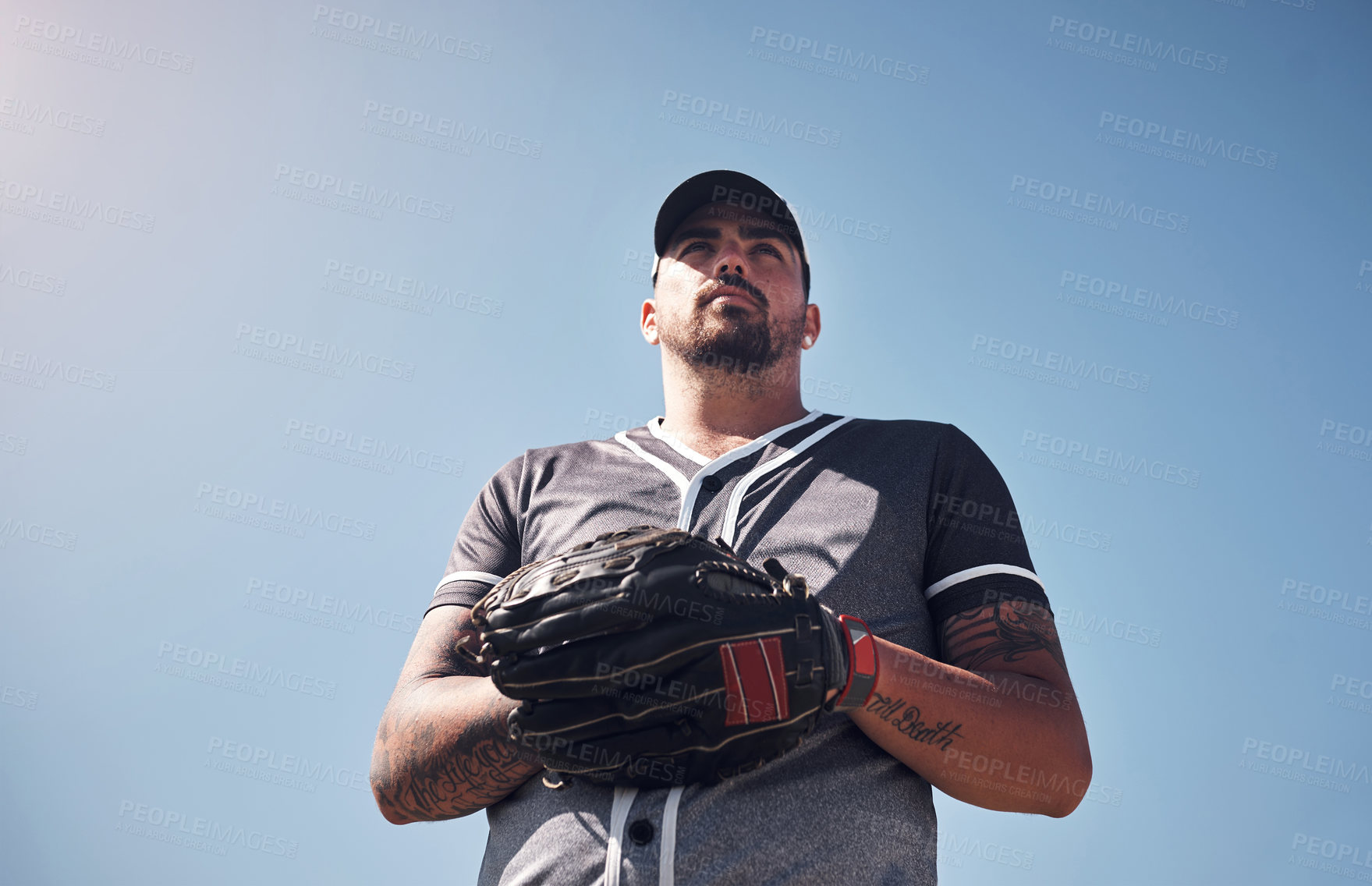 Buy stock photo Man, sports and baseball outdoor with glove for playing game, exercise or club competition on field. Player, determined and softball athlete in stadium with training, low angle and blue sky for pitch