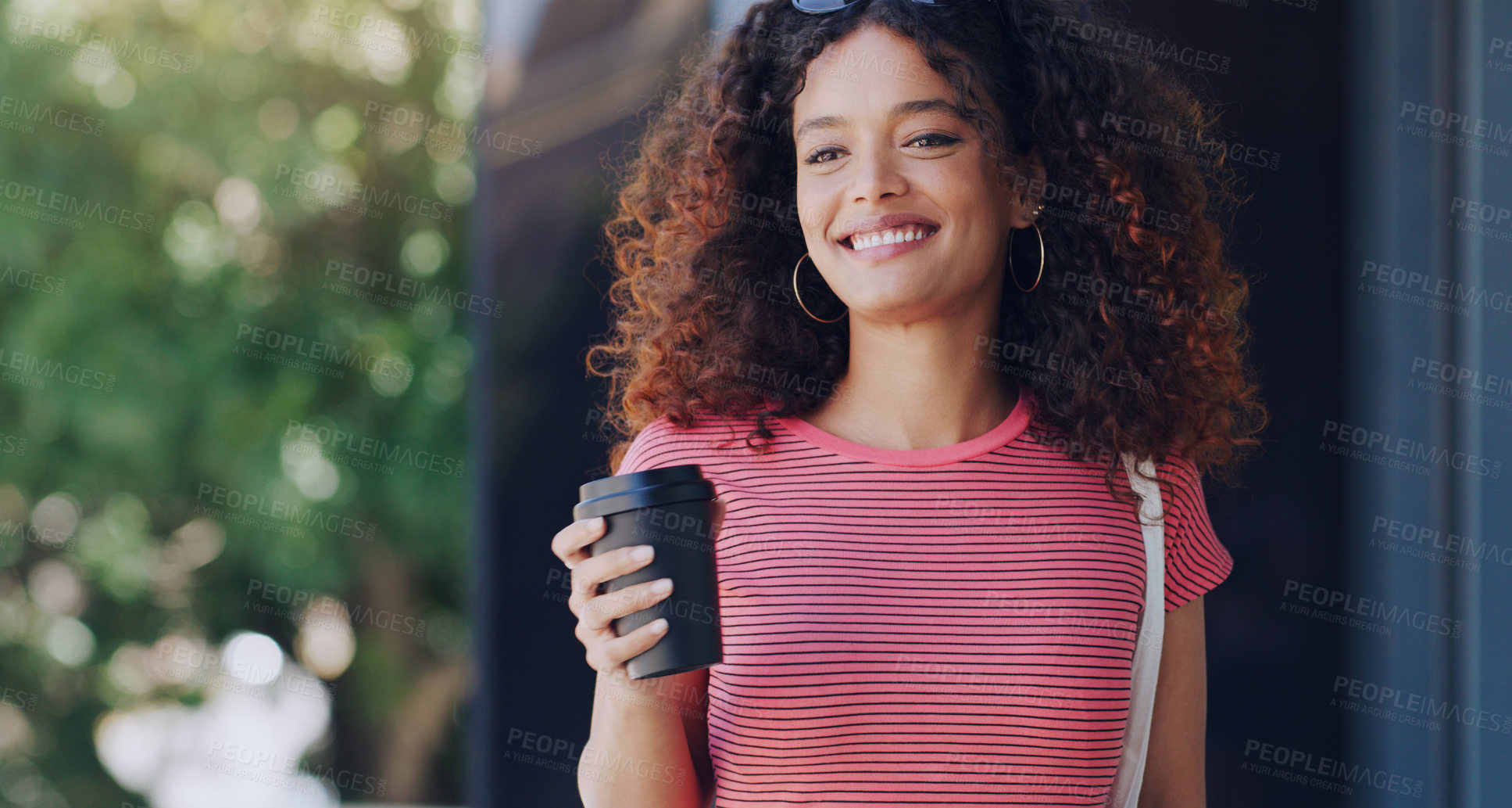 Buy stock photo Cropped shot of a young woman holding a takeout coffee while walking through the city