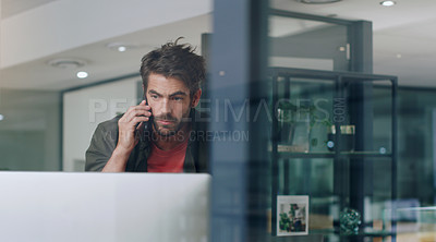Buy stock photo Cropped shot of a handsome young businessman making a phonecall while working on his computer in the office