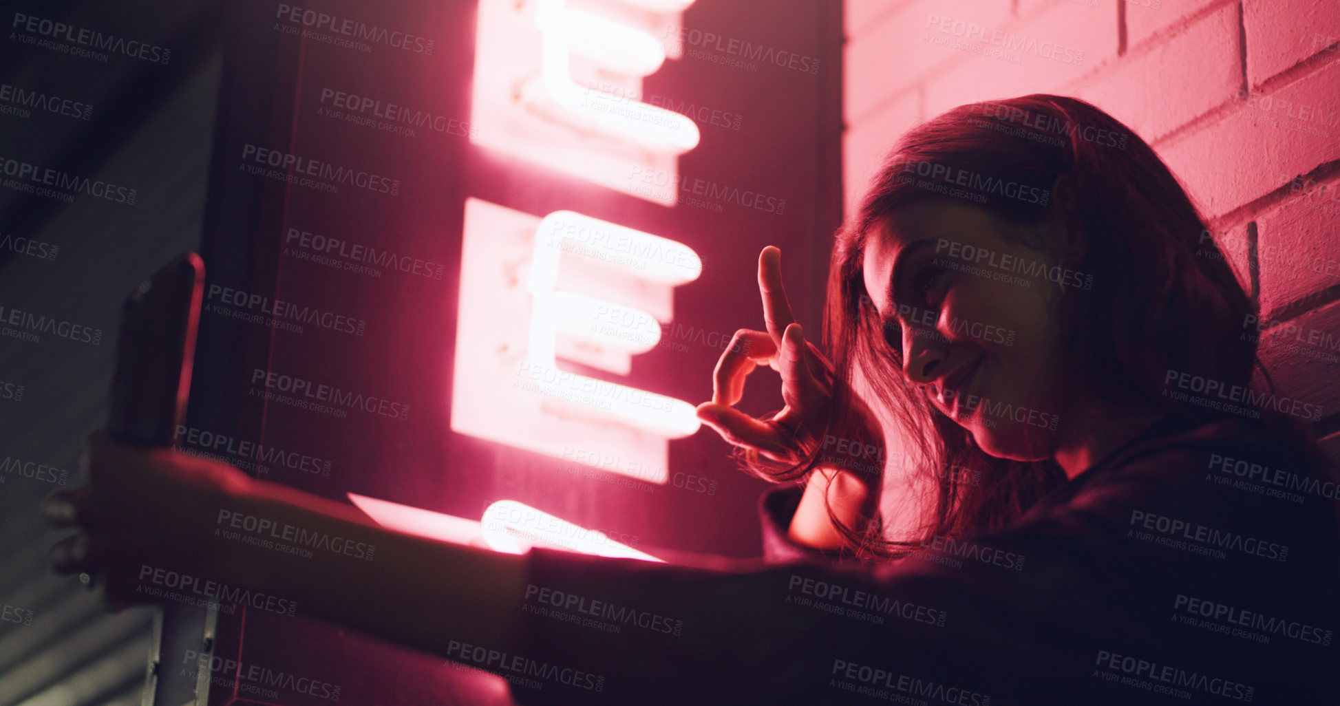 Buy stock photo Shot of a young woman taking a selfie while standing outside a building at night