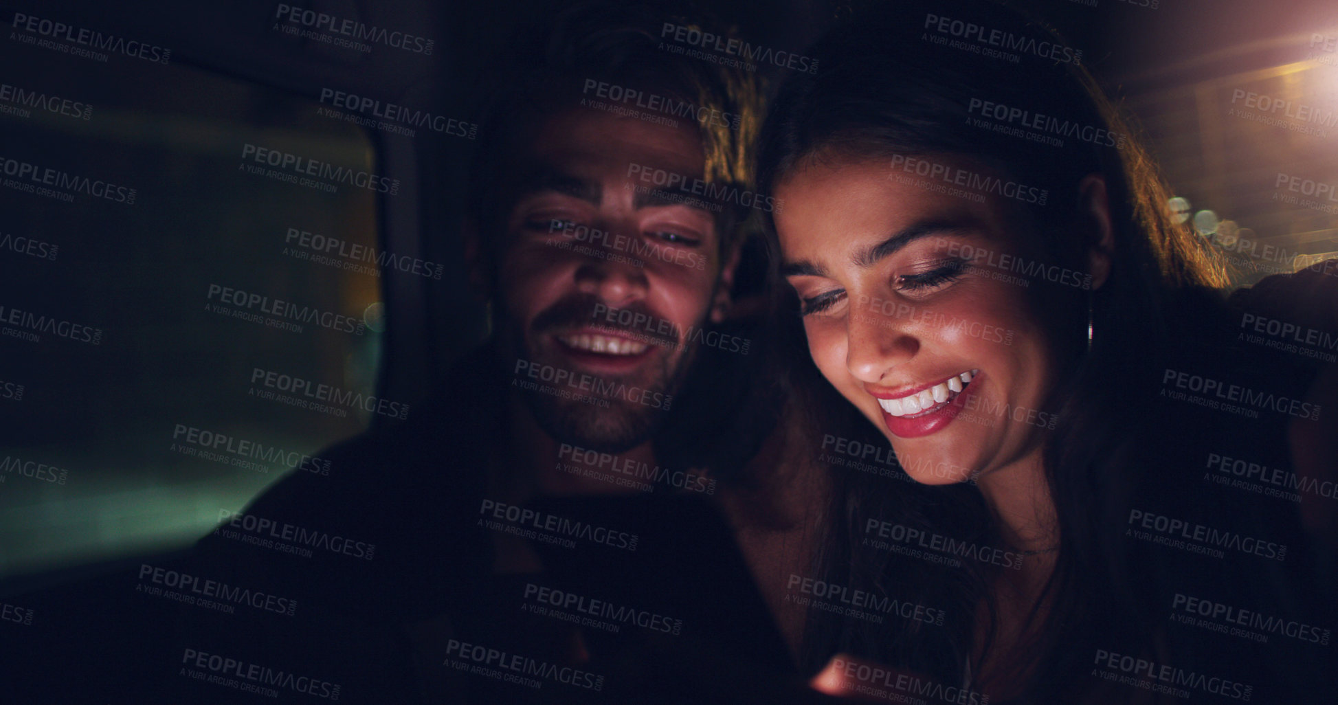 Buy stock photo Shot of a young couple looking at something on a screen while sitting in a car