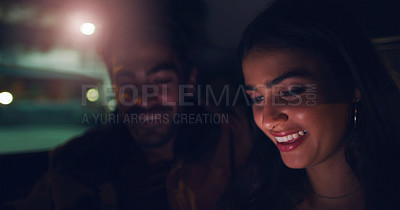 Buy stock photo Shot of a young couple looking at something on a screen while sitting in a car