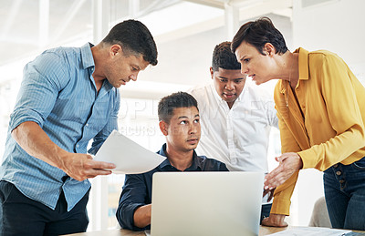 Buy stock photo Shot of a young businessman surrounded by demanding colleagues while working at his desk in an office