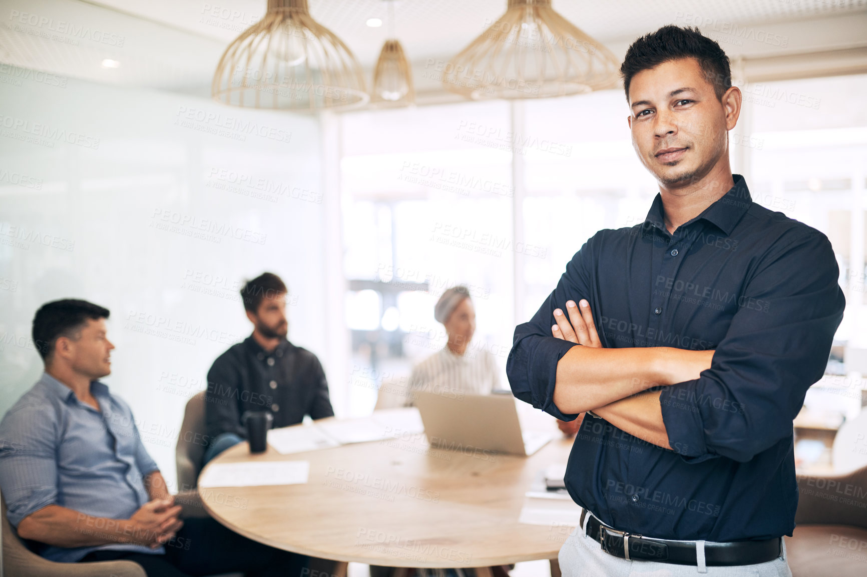 Buy stock photo Portrait of a young businessman standing in an office with his colleagues in the background