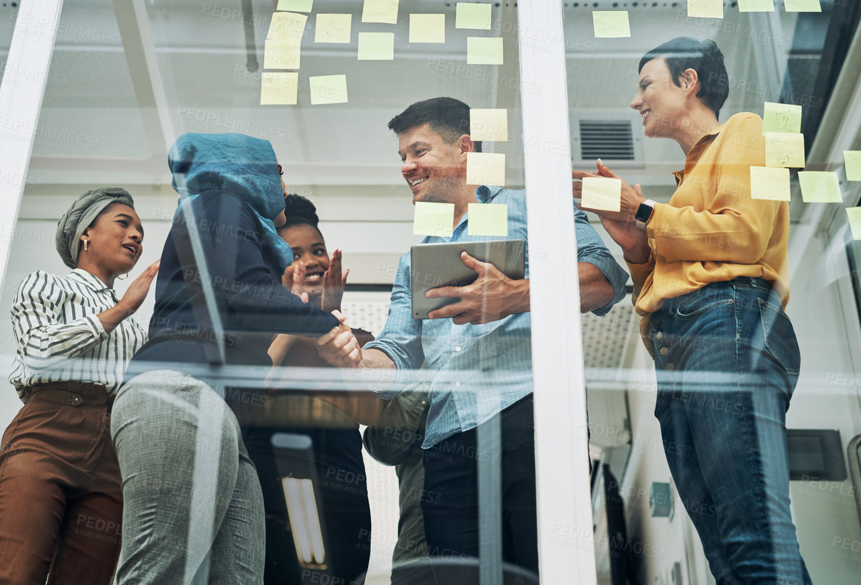 Buy stock photo Shot of a group of businesspeople applauding their colleagues while brainstorming on a glass wall in an office
