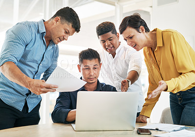 Buy stock photo Shot of a young businessman surrounded by demanding colleagues while working at his desk in an office