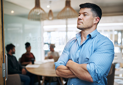 Buy stock photo Shot of a mature businessman standing in an office with his colleagues in the background
