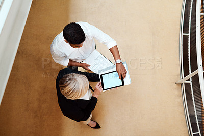 Buy stock photo High angle shot of two businesspeople using a digital tablet together in an office
