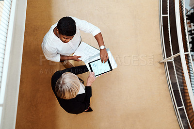 Buy stock photo High angle shot of two businesspeople using a digital tablet together in an office