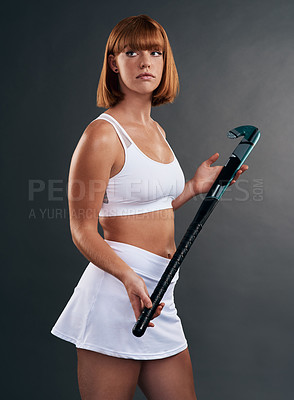 Buy stock photo Studio shot of an attractive young woman posing with a hockey stick against a grey background