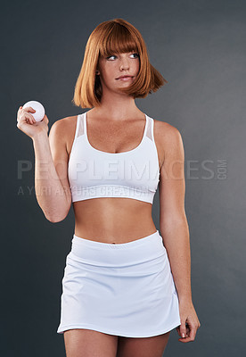 Buy stock photo Shot of a sporty young woman posing with a ball against a grey background