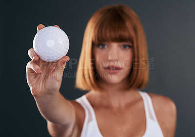 Buy stock photo Shot of a sporty young woman posing with a ball against a grey background