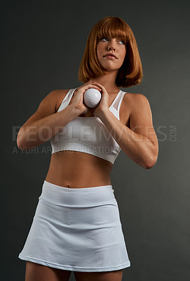 Buy stock photo Shot of a sporty young woman posing with a ball against a grey background